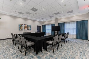 Une salle de conférence équipée d’une grande table, de chaises, d’un téléviseur à écran plat et ornée d’œuvres d’art sur les murs.