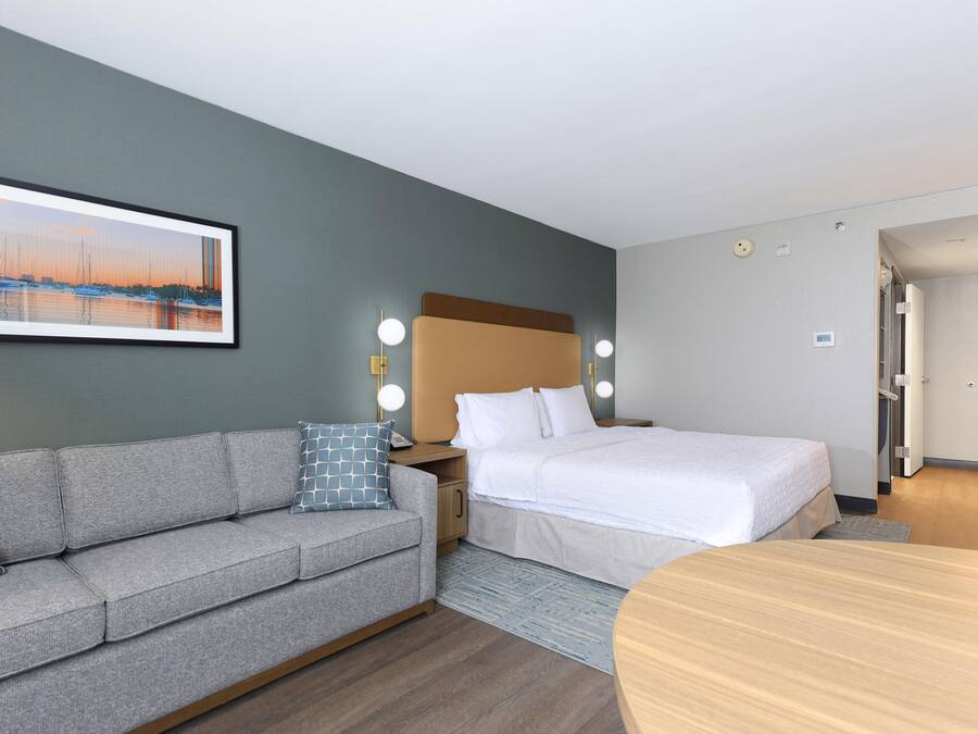 Una habitación de hotel con una cama, un sofá, una mesa y un cuadro en la pared.