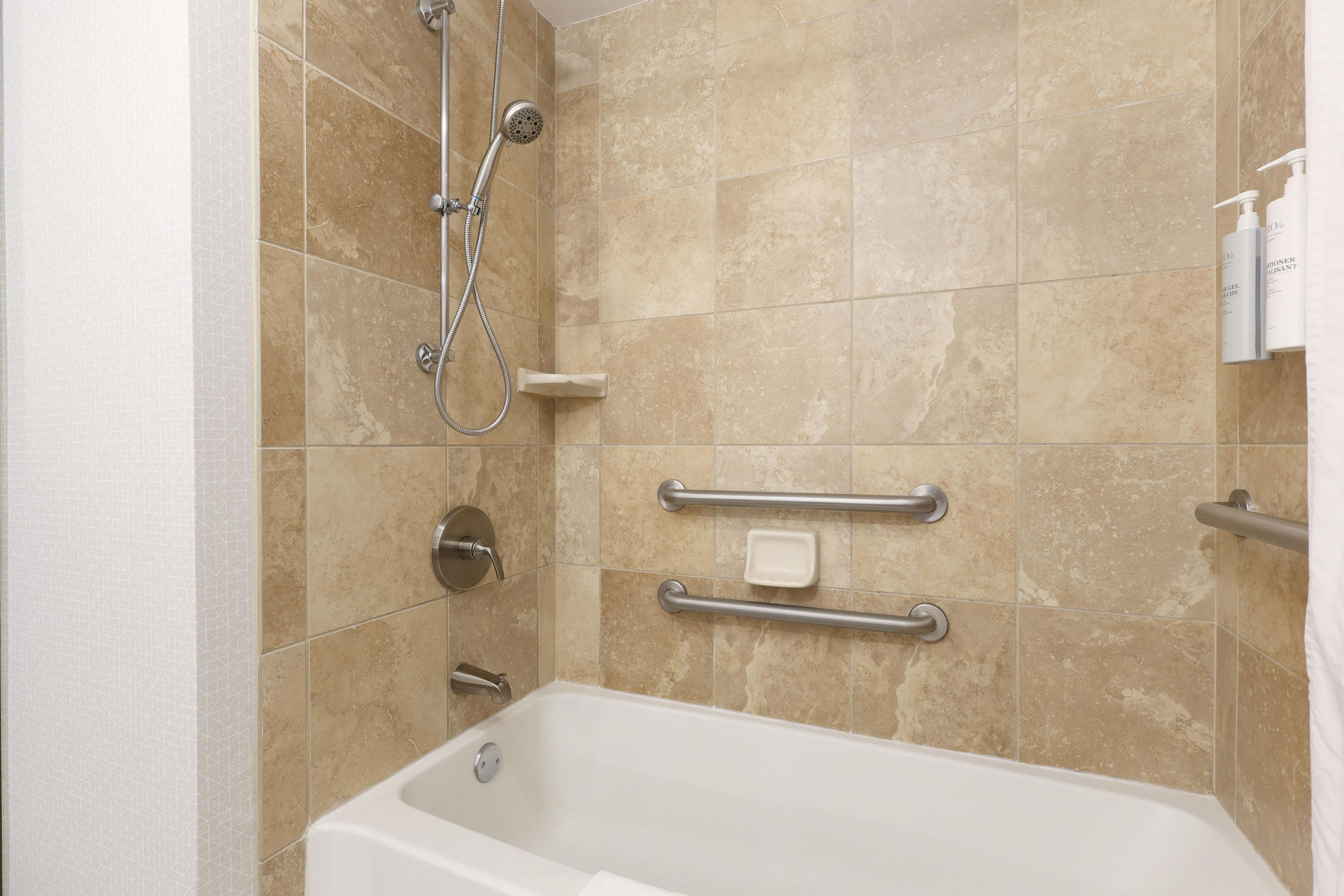 Ein modernes Badezimmer mit Badewanne, Dusche und Haltegriffen für Barrierefreiheit.