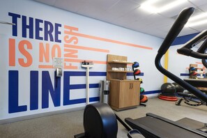 Une salle de sport dotée d’un mur d’inspiration, d’appareils d’exercice et d’un bureau avec un téléphone.