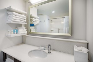 A modern bathroom with a large mirror, white sink, and towel storage. - Hampton Inn Dover (Dover)