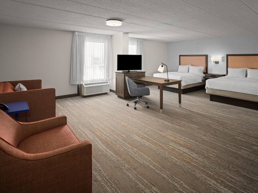 A hotel room with a bed, a desk, a chair, a television, and a window with curtains.