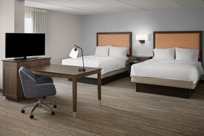 Une chambre d’hôtel avec un bureau, deux lits, une télévision et une chaise.