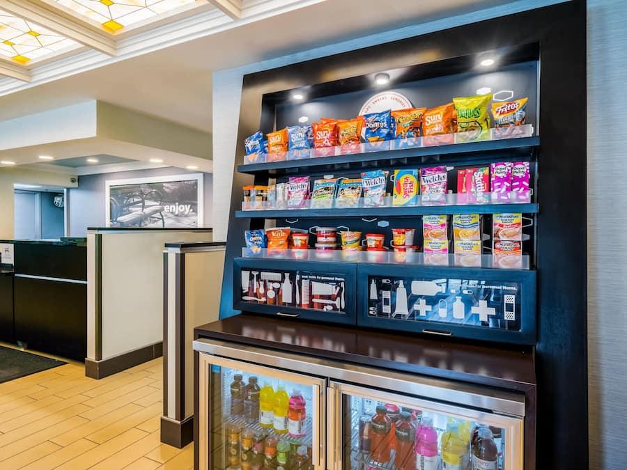 A snack display with various brands and a refrigerated section with beverages.