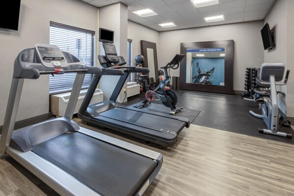 Un gimnasio con cintas de correr, elípticas y bicicletas estáticas.