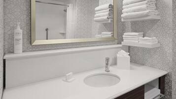 A bathroom with a large mirror, a sink, a towel rack, and a bottle of body lotion.