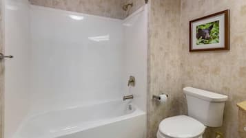 Un baño con bañera, inodoro y un cuadro en la pared.