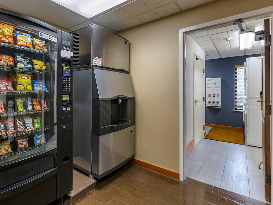 Eine Küchenzeile mit einem Getränkeautomaten, der mit Snacks gefüllt ist, einem Kühlschrank und einer Tür zu einem Badezimmer.
