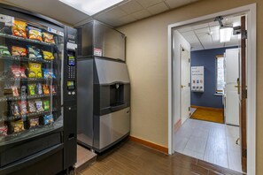 A kitchenette with a vending machine stocked with snacks, a refrigerator, and a door leading to a bathroom. - Comfort Inn Missoula North Shopping District (Missoula)
