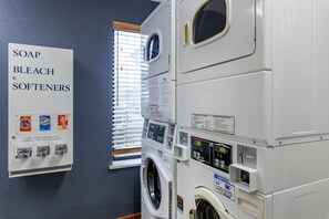 A laundry facility with stacked washers and dryers, a coin-operated soap and detergent dispenser, and operating instructions. - Comfort Inn Missoula North Shopping District (Missoula)
