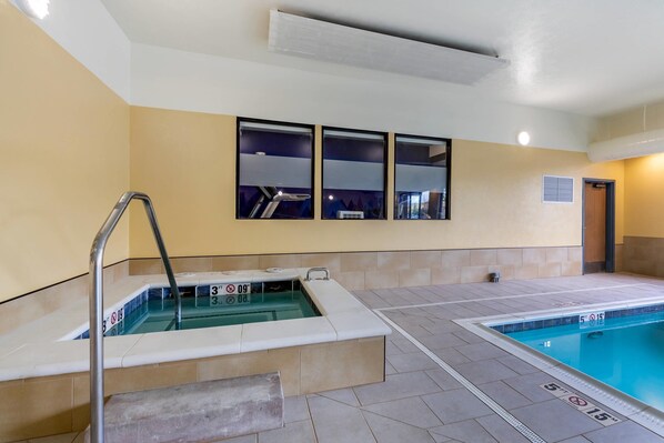 A swimming pool with a diving board and a hot tub.