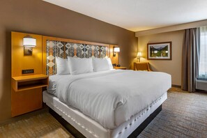 A hotel room with a large bed, bedside tables, a wall-mounted lamp, and a painting. - Comfort Inn Missoula North Shopping District (Missoula)