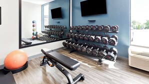 A gym with a bench, exercise ball, and dumbbells on shelves. - Hampton Inn Washington (Washington)
