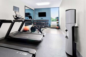 A gym with treadmills, a stationary bike, and a wall-mounted TV.