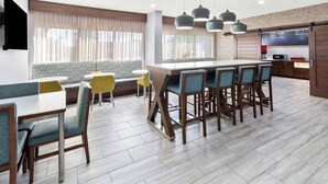 A modern dining area with a central island, bar stools, and a kitchen area with a chalkboard menu. - Hampton Inn Washington (Washington)