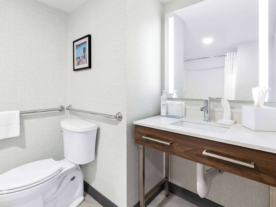 Un baño moderno con inodoro blanco, tocador de madera con espejo y perchero.
