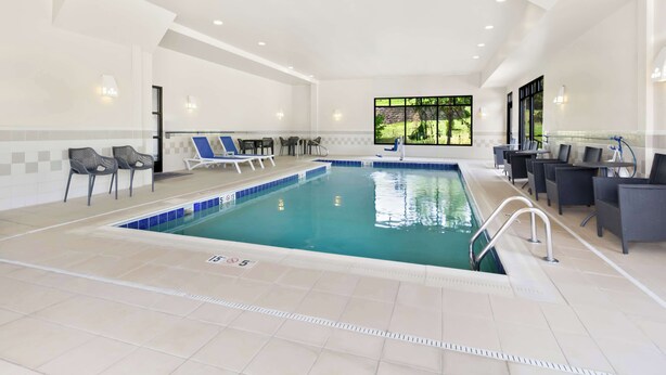 An indoor swimming pool with lounge chairs and a bar area. - Hampton Inn Washington (Washington)