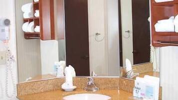 A bathroom with a granite countertop, a white sink, a mirror, and a towel rack.