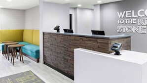 A reception area with a modern design, including a reception desk, seating area with a sofa and tables, and a wall with a welcome sign. - Hampton Inn Washington (Washington)