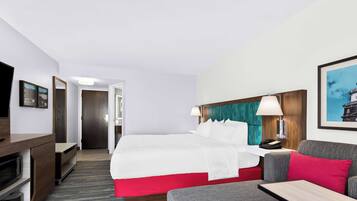 Una habitación de hotel con cama, escritorio, televisor y sofá.