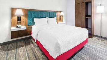 Habitación de hotel con una cama grande, dos mesitas de noche con lámparas, un cabecero de madera y un armario.
