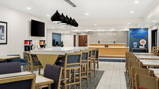 A modern hotel lobby with a reception desk, seating area, and a coffee station. - Hampton Inn Provo (Provo)