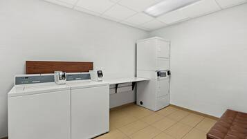 Een wasserette met een wasmachine, droger en een kast.