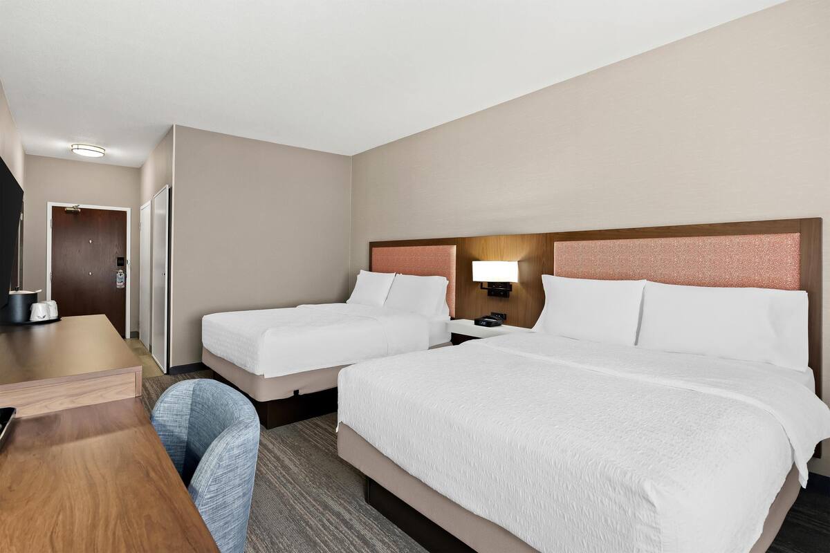 Une chambre d’hôtel avec deux lits, un bureau et une chaise.