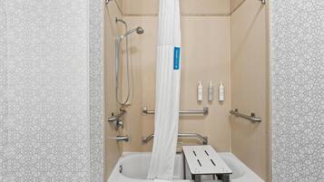 A modern bathroom with a shower, grab bars, and a white towel.