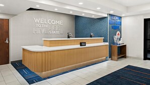 A reception desk with a wooden finish, a "Welcome to the Bee Hive State" sign, and a "Making Your Happy Mates is Happy" sign. - Hampton Inn Provo (Provo)