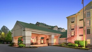 A hotel entrance with a green roof, a flagpole with an American flag, and a clear sky. - Hampton Inn & Suites Nashville/Franklin (Cool Springs) (Franklin)