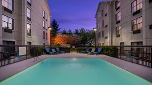 A swimming pool with lounge chairs and a fence, surrounded by buildings and trees. - Hampton Inn & Suites Nashville/Franklin (Cool Springs) (Franklin)
