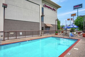 Un hotel con piscina, mobiliario exterior y un letrero de Ruby Tuesday.