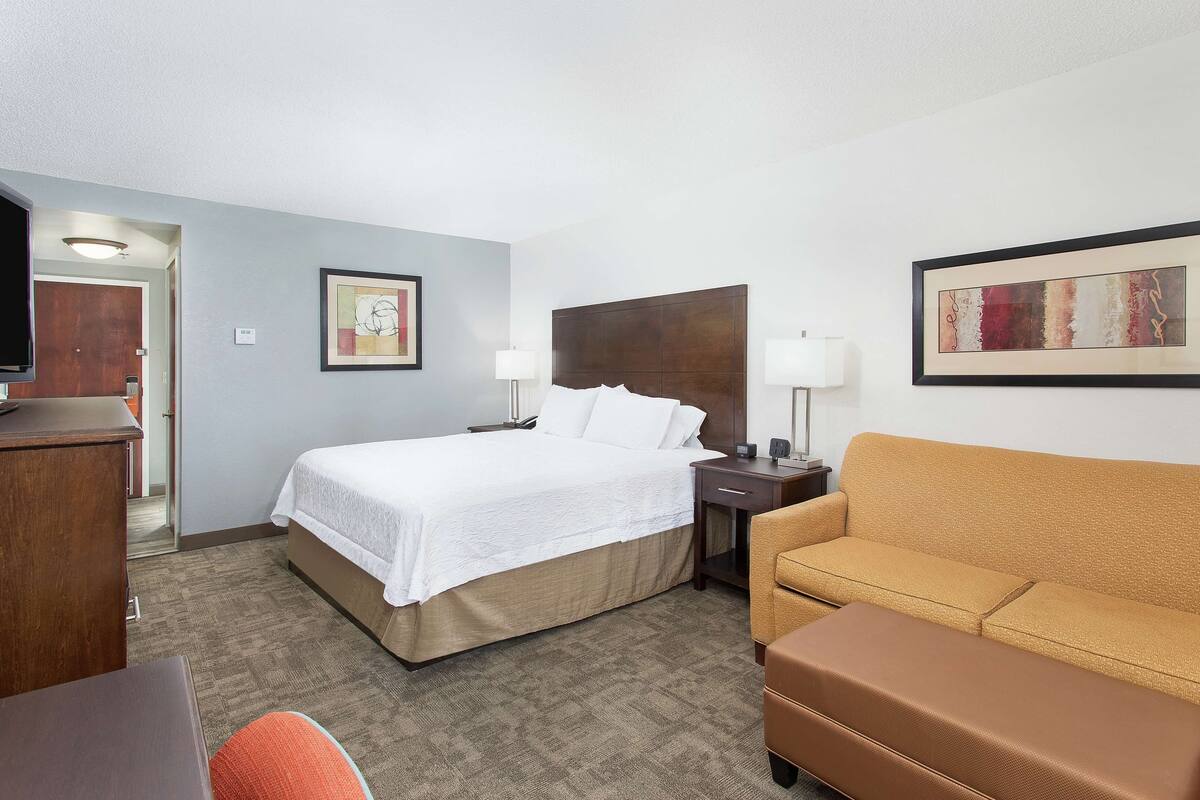 Una habitación de hotel con cama, sofá, escritorio y dos lámparas.