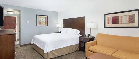 Una habitación de hotel con cama, sofá, escritorio y dos lámparas.