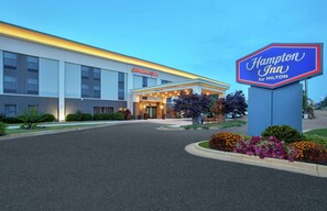 A Hampton Inn by Hilton building with a welcoming entrance and a clear sky.