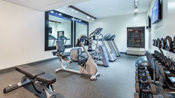 A gym with exercise equipment, mirrors, and a television on the wall. - Hampton Inn Cullman (Cullman)