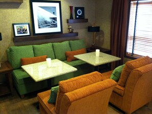 Ein Wohnzimmer mit einem grünen Sofa, zwei passenden Sesseln, einem Couchtisch und einem gerahmten Bild an der Wand.