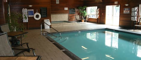 An indoor swimming pool with wooden walls, a lifeguard chair, and a notice board.