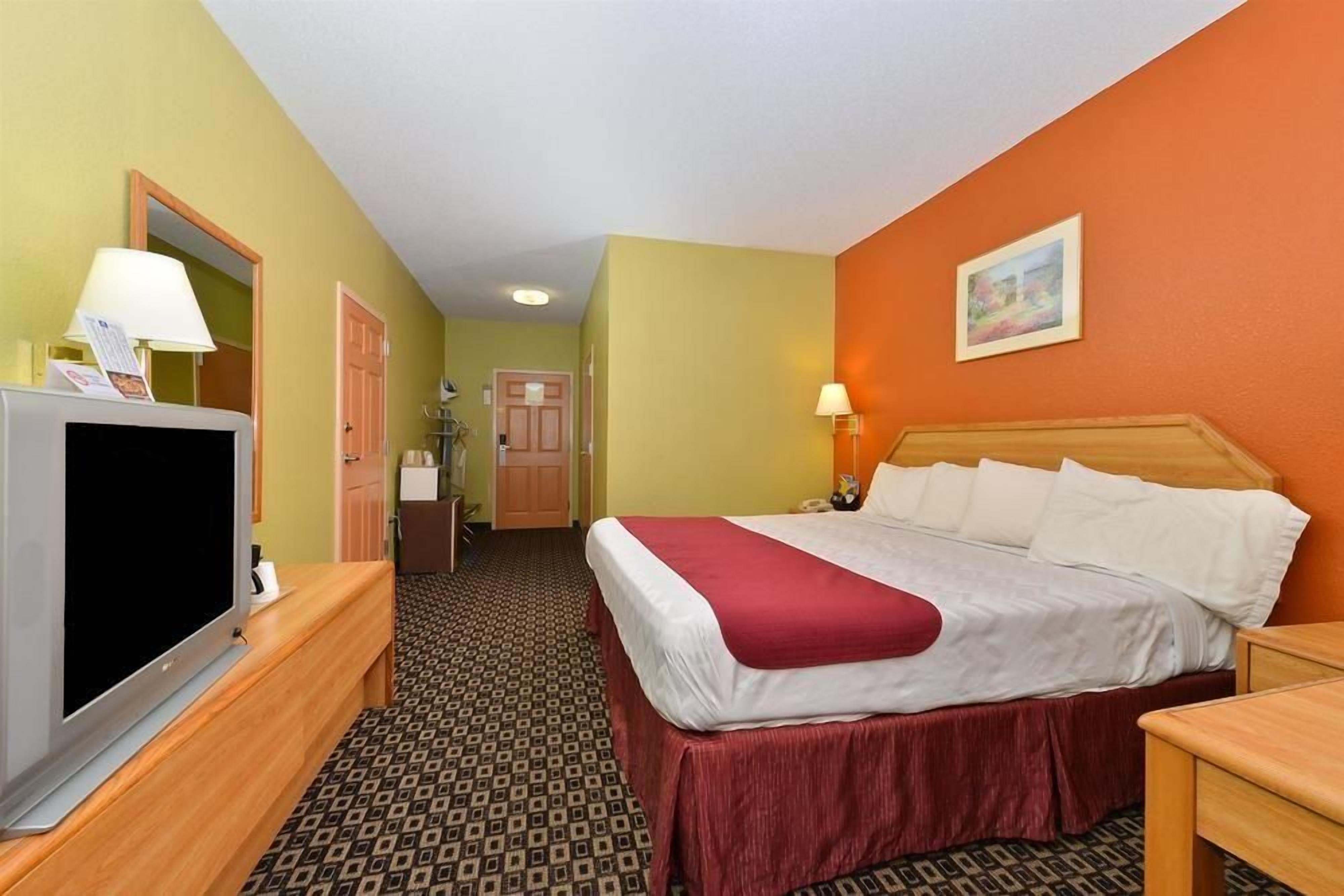 A hotel room with a bed, a television, a desk, and a bathroom.