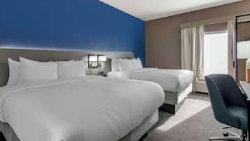 A hotel room with two beds, a desk, and a chair.