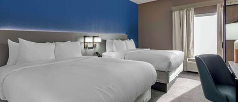 A hotel room with two beds, a desk, and a chair.