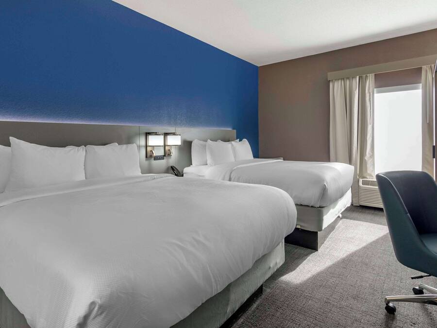 Ett hotellrum med två sängar, ett skrivbord och en stol.