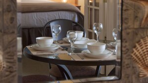 Une chambre d’hôtel avec une table à manger bien rangée, un lit avec une tête de lit et une lampe de chevet.