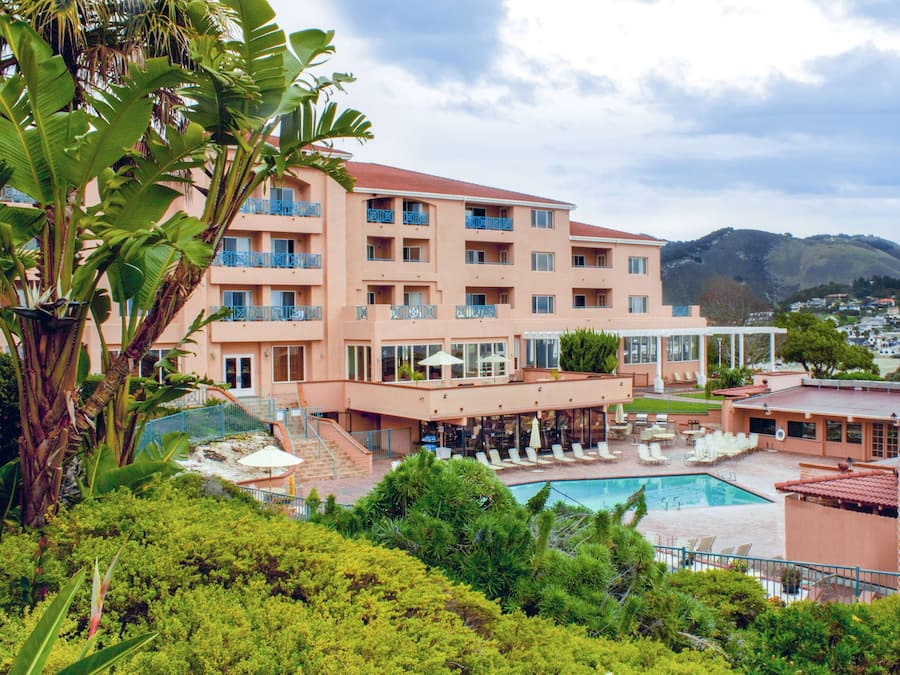 Un hotel con piscina, mobiliario exterior y vistas a la montaña.