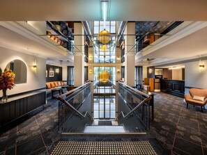 A spacious hotel lobby with a central staircase, multiple seating areas, and a reception desk. - Mantra on Jolimont Melbourne (East Melbourne)