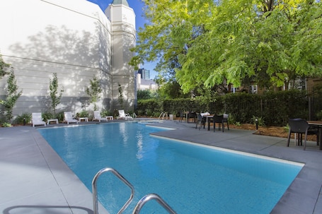 Una piscina al aire libre, sillones reclinables de piscina