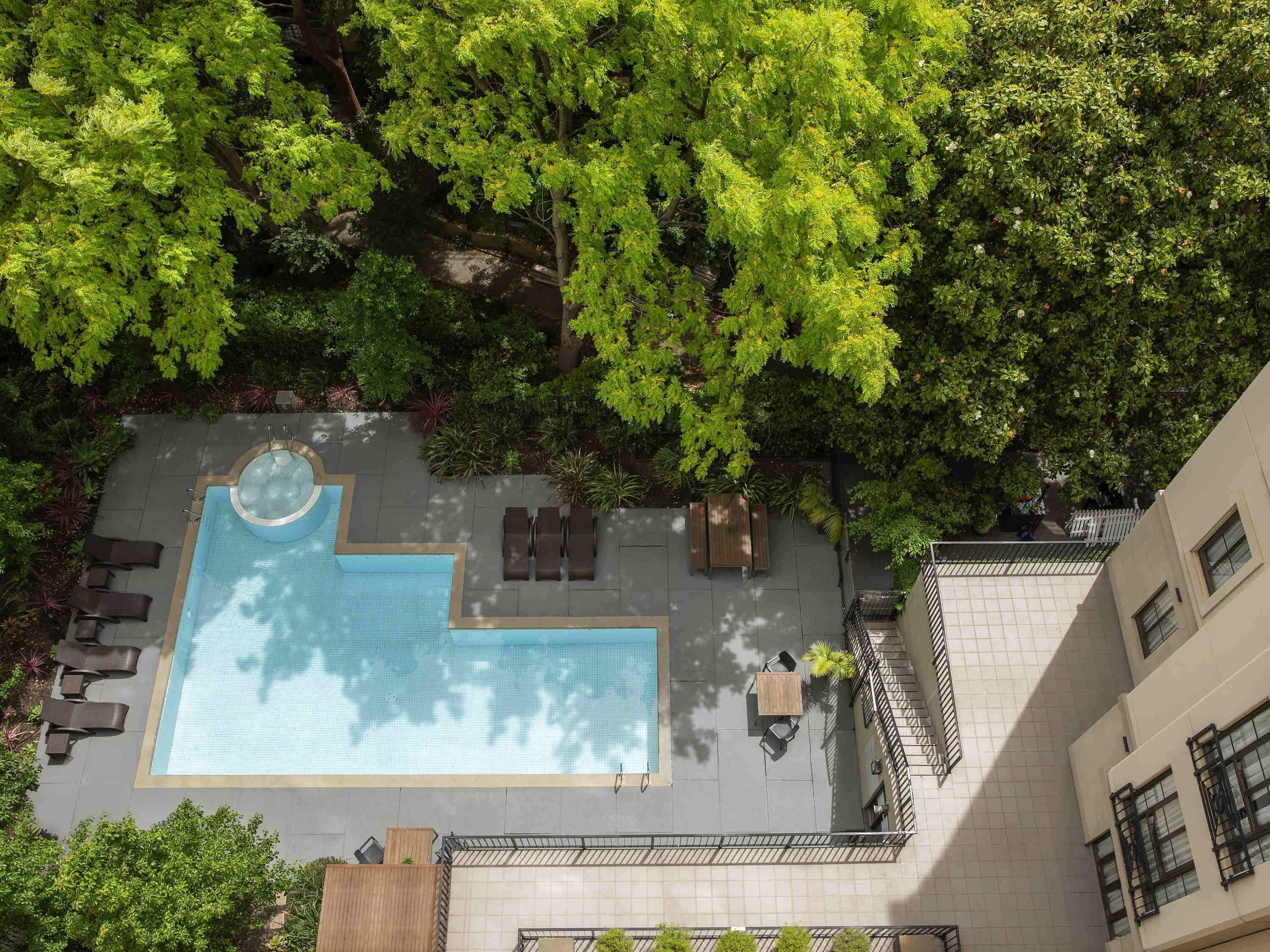 An aerial view of a rooftop pool area with a hot tub, lounge chairs, and a seating area.