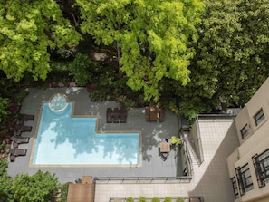An aerial view of a rooftop pool area with a hot tub, lounge chairs, and a seating area.