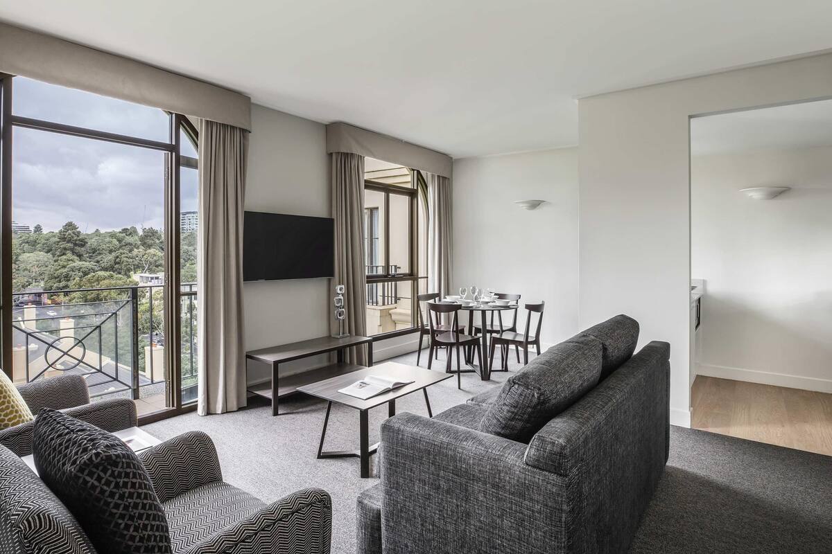 Een moderne hotelkamer met balkon, een zithoek en een grote televisie.